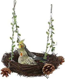 Two birds sitting in a decorative swing perch made of woven twigs with pine cones and hanging vines.