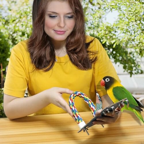 Woman holding a colorful perch with a parrot sitting on it.